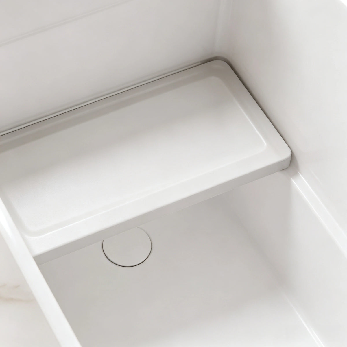 Interior seat and drain detail inside the glossy white compact bathtub.