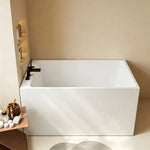 Compact back-to-wall bathtub in a small bathroom with a deck-mounted faucet.