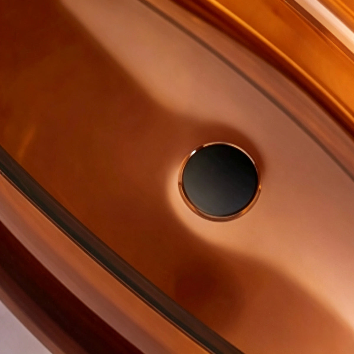 Close-up of the dark drain inside the transparent brown resin bathtub.