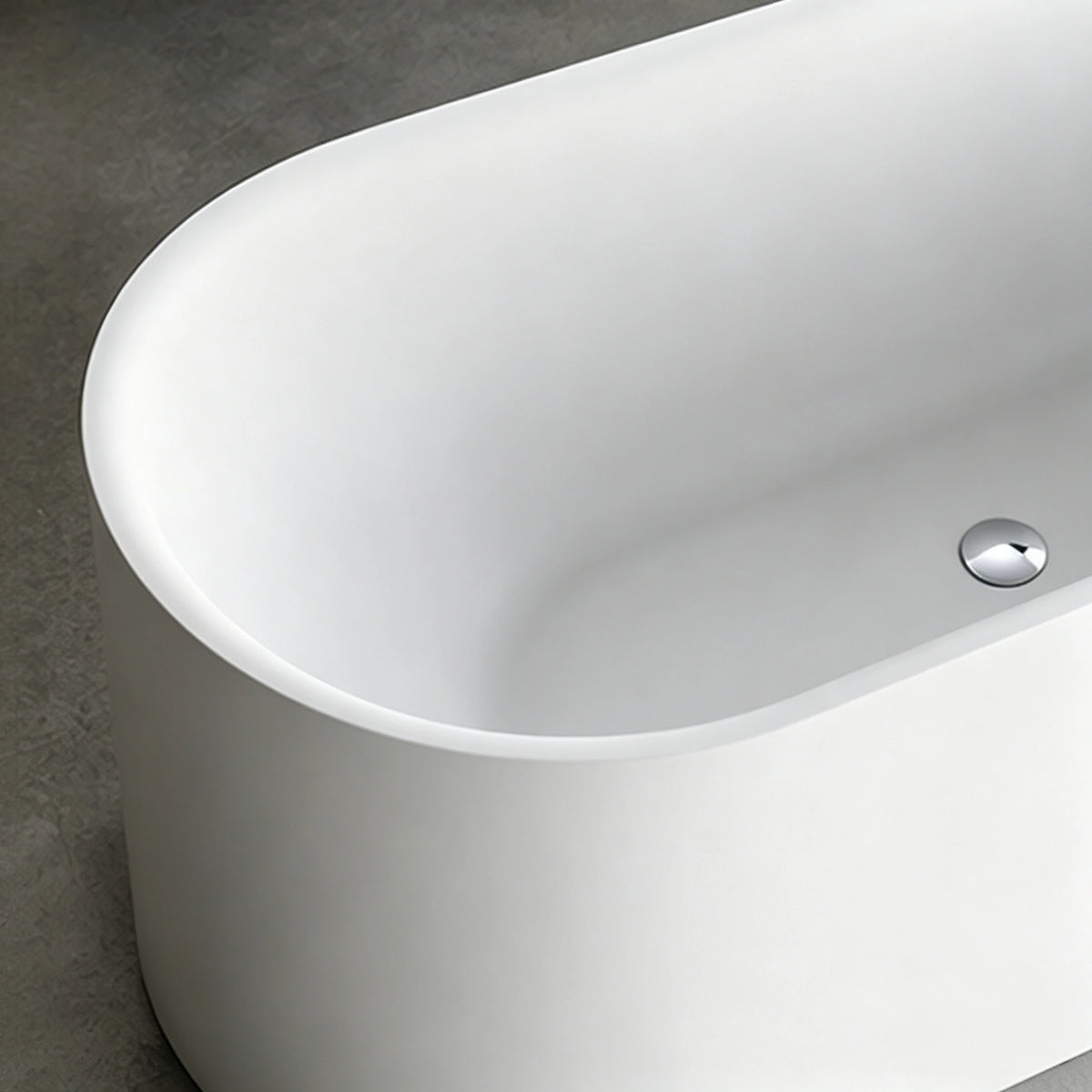 Close-up of the chrome drain and slim rim inside the oval bathtub.