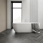 Thin-rim solid surface freestanding bathtub in a minimalist bathroom.