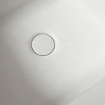 Close-up of the color-matched drain inside the matte white bathtub.
