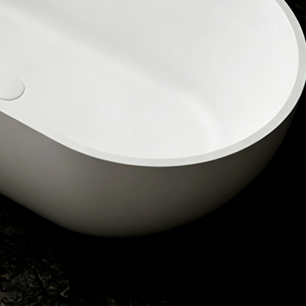 Close-up of the thin rim and rounded exterior of the solid surface bathtub.