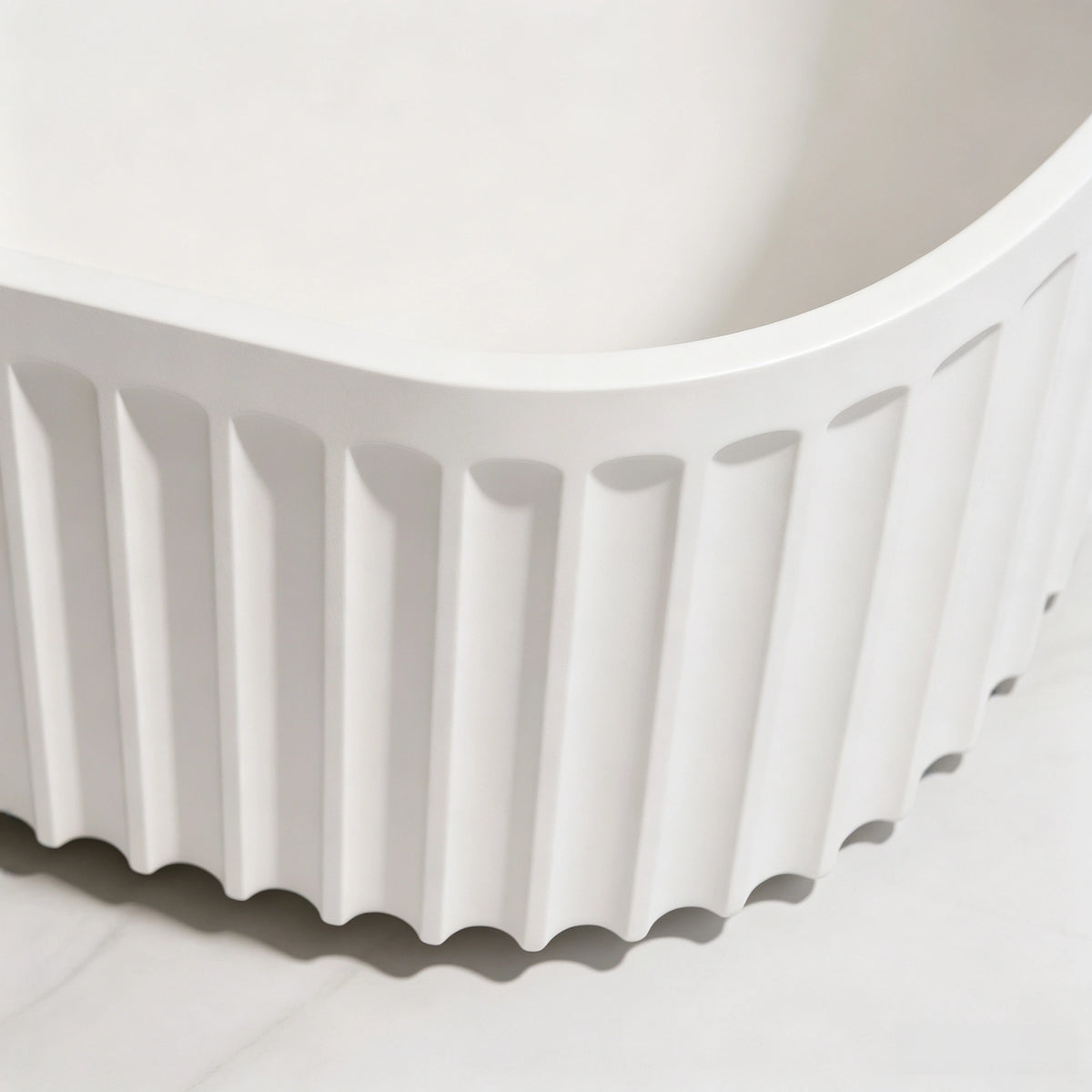 Close-up of the rounded corner and vertical fluting on the bathtub exterior.
