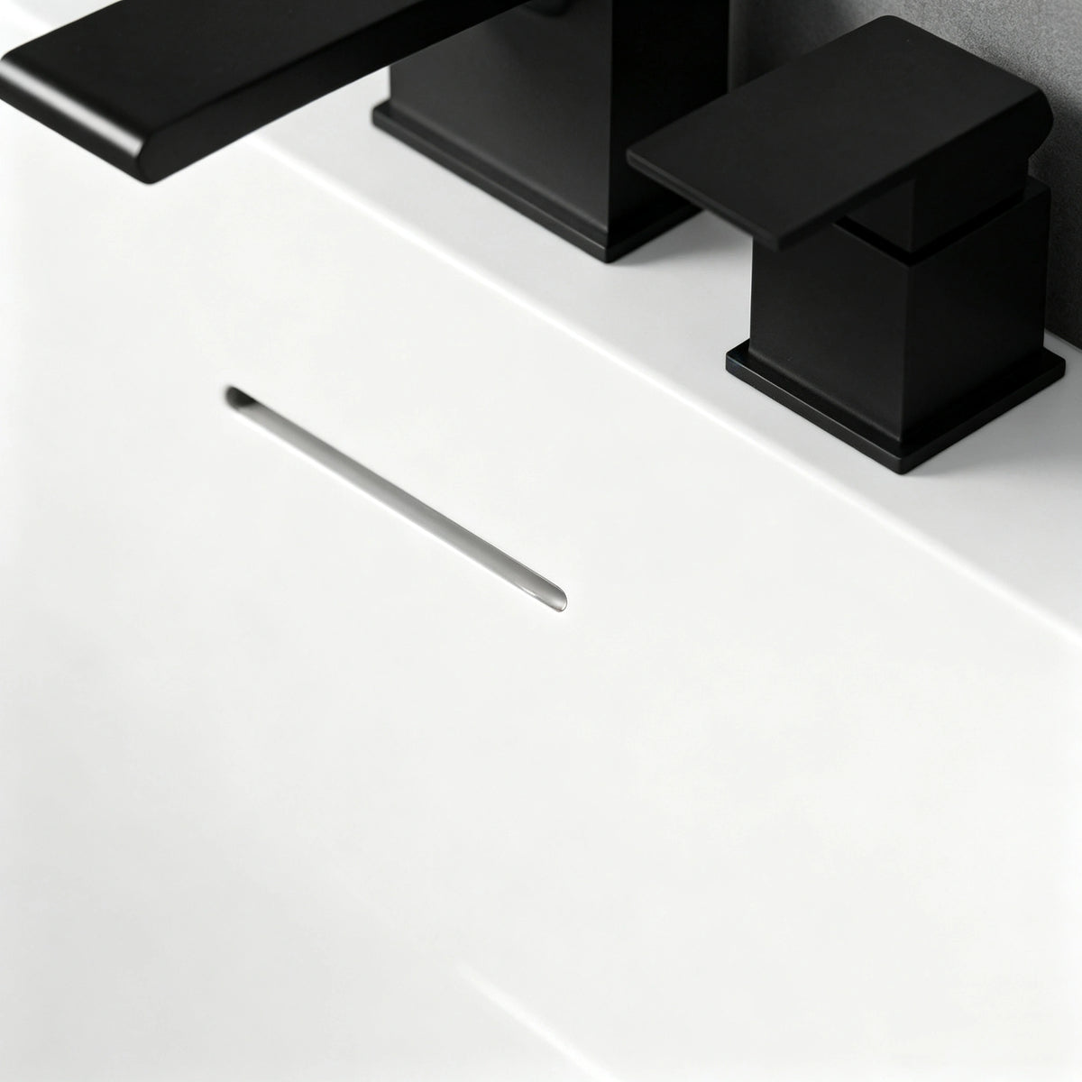 Close-up of the slot overflow and black deck-mounted faucet.