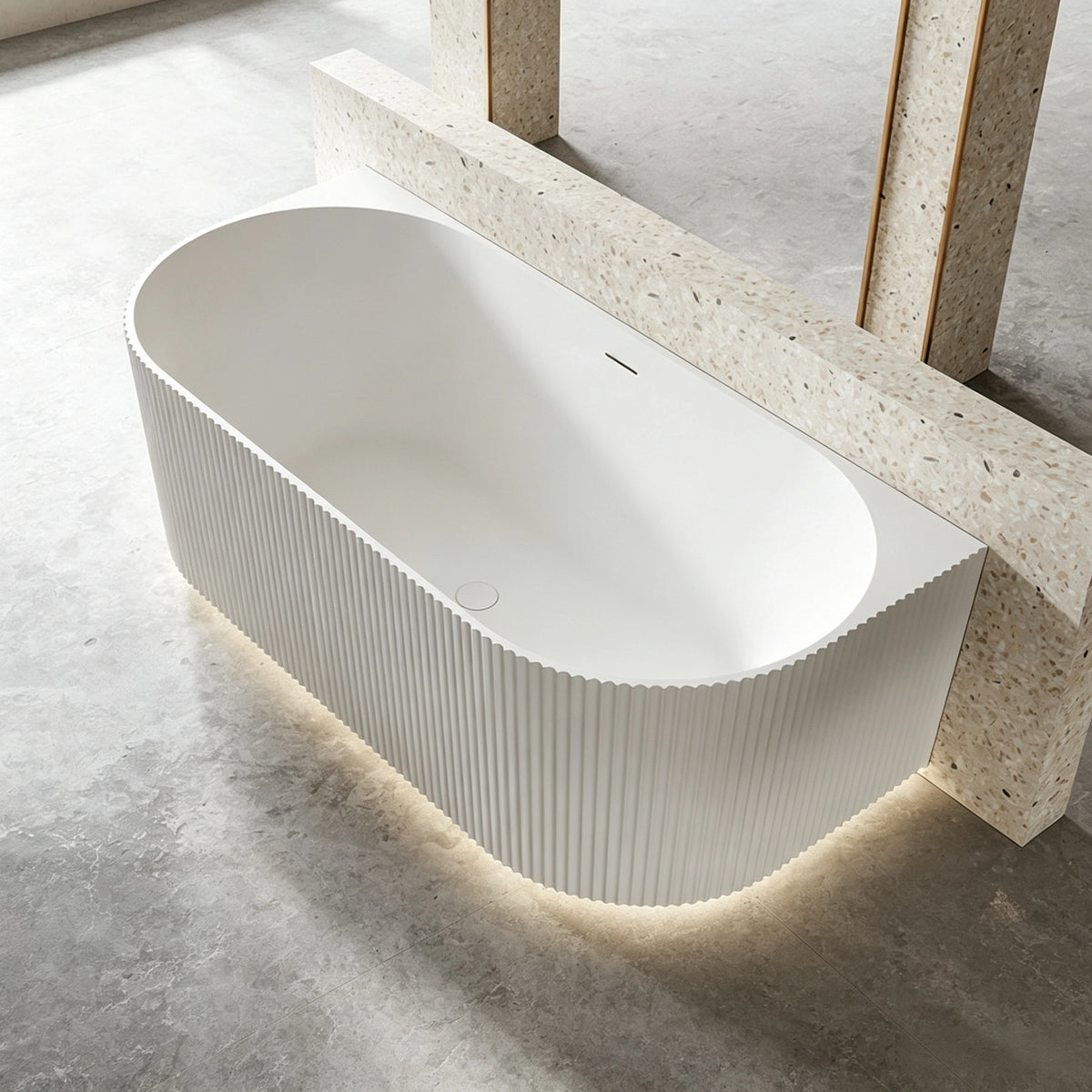 Top view of the ribbed bathtub installed against a terrazzo half wall.