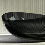 Side view showing the raised end and curved rim of the black bathtub.