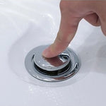 Close-up of push-to-open chrome drain on white bathtub surface