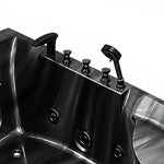 Close-up of bathtub rim black hardware knobs, spout, hand shower and internal massage jets