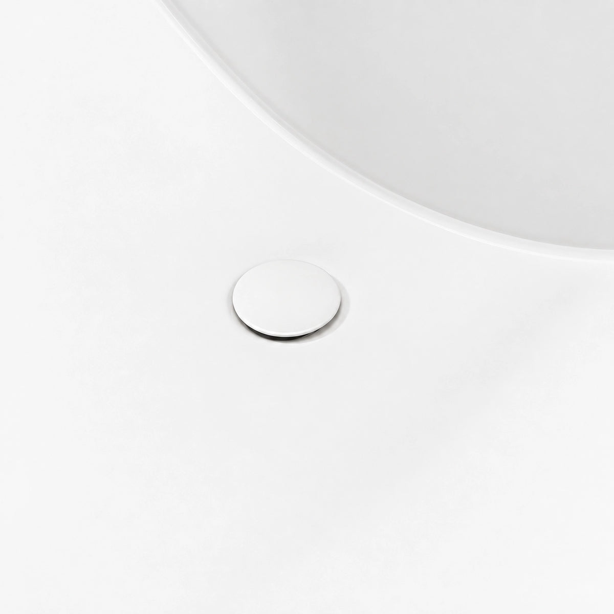 Bathtub interior close-up, matching white round drain cover on smooth solid surface tub surface