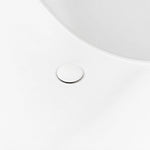 Bathtub interior close-up, matching white round drain cover on smooth solid surface tub surface