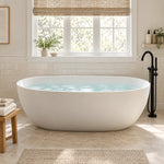 White oval freestanding bathtub placed in bright bathroom with large window, tiled wall and woven decor