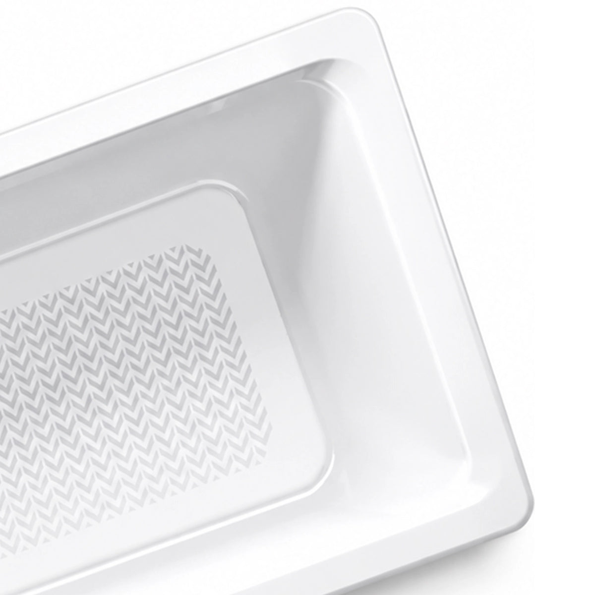 Corner close-up of bathtub, smooth white tub body, sloped inner wall and chevron textured anti-slip bottom