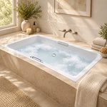 Drop-in bathtub in window-side bathroom, light beige tile wall, countertop decorated with candles and plants