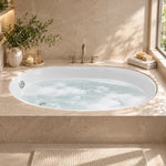 Oval drop-in bathtub set in beige marble bathroom countertop, natural window light, with deck-mounted faucet and bath decor