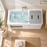 Rectangular bathtub with side rack, installed in bright bathroom with light wood flooring and small round side table