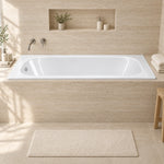 Drop-in rectangular acrylic bathtub fitted in light beige stone tiled bathroom with built-in wall niche and soft natural lighting