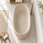 Top-down view of oval solid freestanding bathtub in bathroom with herringbone marble tile floor