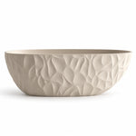 Freestanding oval tub in light beige, featuring one-piece sculptural embossed outer surface