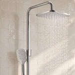 Chrome square shower system spraying water on tiled bathroom wall