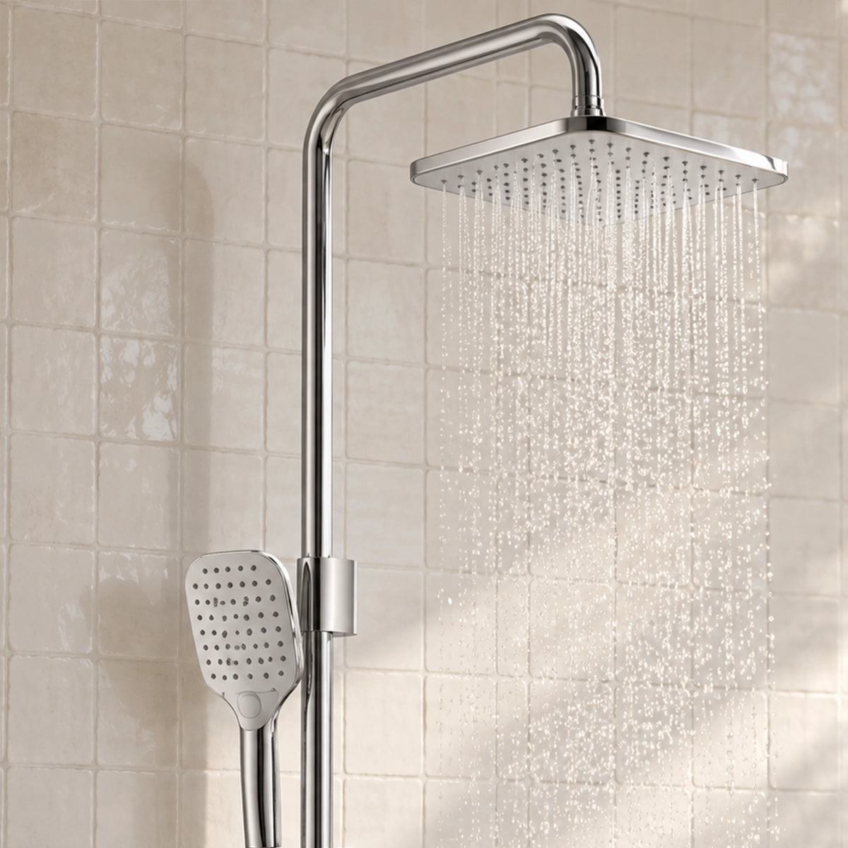 Chrome square shower system spraying water on tiled bathroom wall
