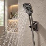 Handheld shower spraying water in herringbone tile bathroom