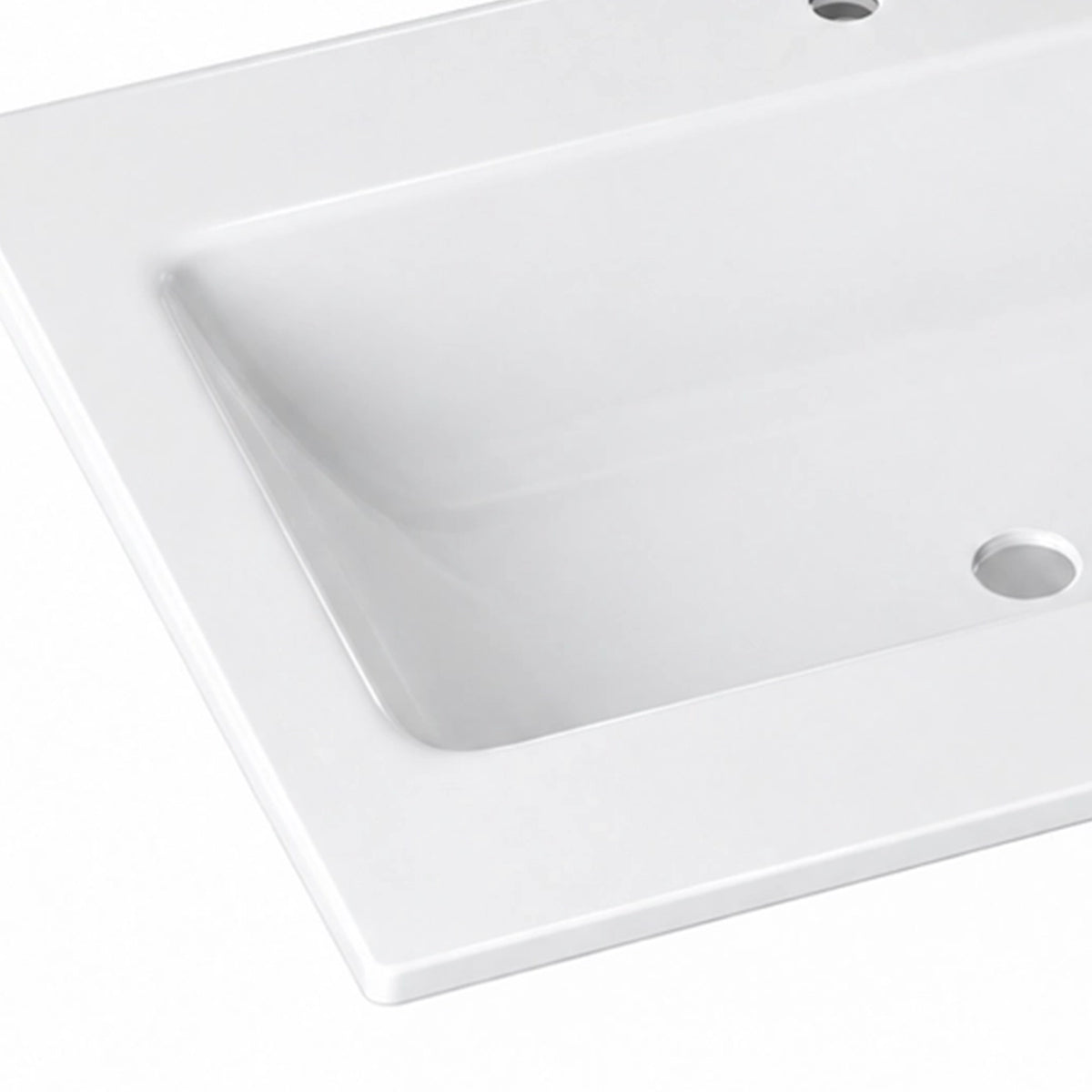 Close-up shot of glossy white ceramic drop-in vanity sink, showing curved basin corner and drain hole