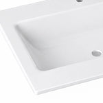 Close-up shot of glossy white ceramic drop-in vanity sink, showing curved basin corner and drain hole