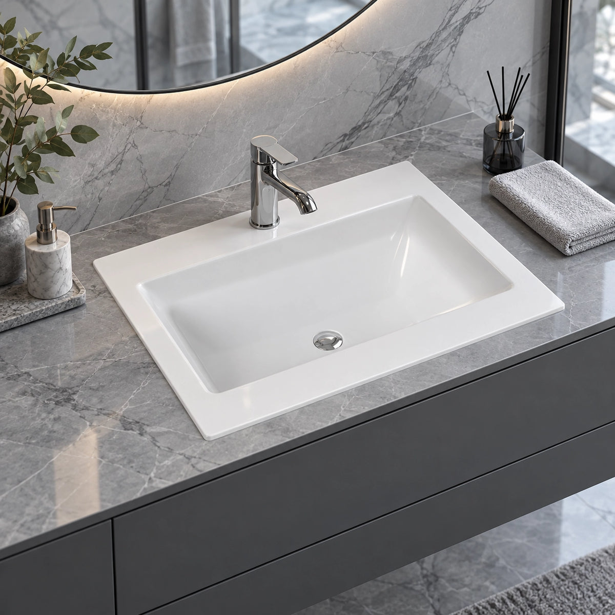 Close view of white ceramic drop-in vanity sink on marble bathroom countertop