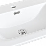 Close-up of white ceramic sink with overflow hole and drain detail