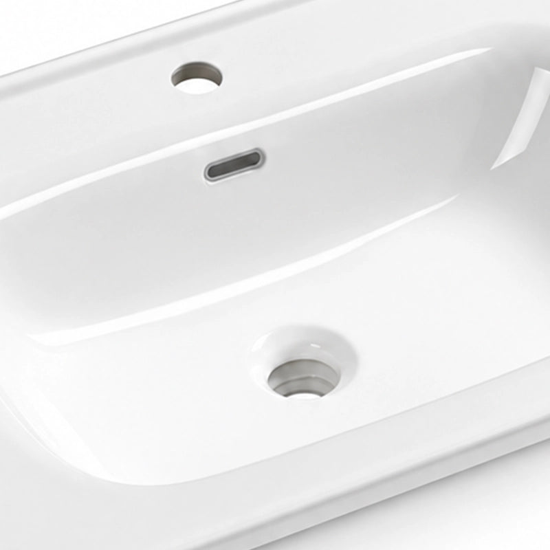 Glossy white ceramic sink interior close-up, featuring overflow slot, faucet hole and drain hole