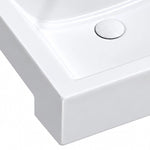 Close-up view of glossy white ceramic semi-recessed bathroom sink basin and drain cover