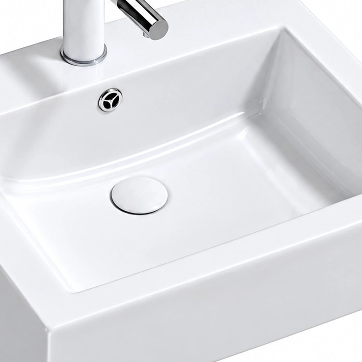 Close-up of glossy white rectangular ceramic semi-recessed sink basin with built-in overflow and drain