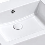 Close-up of the white rectangular ceramic semi-recessed bathroom sink showing the integrated overflow opening, smooth basin surface, and drain cover.