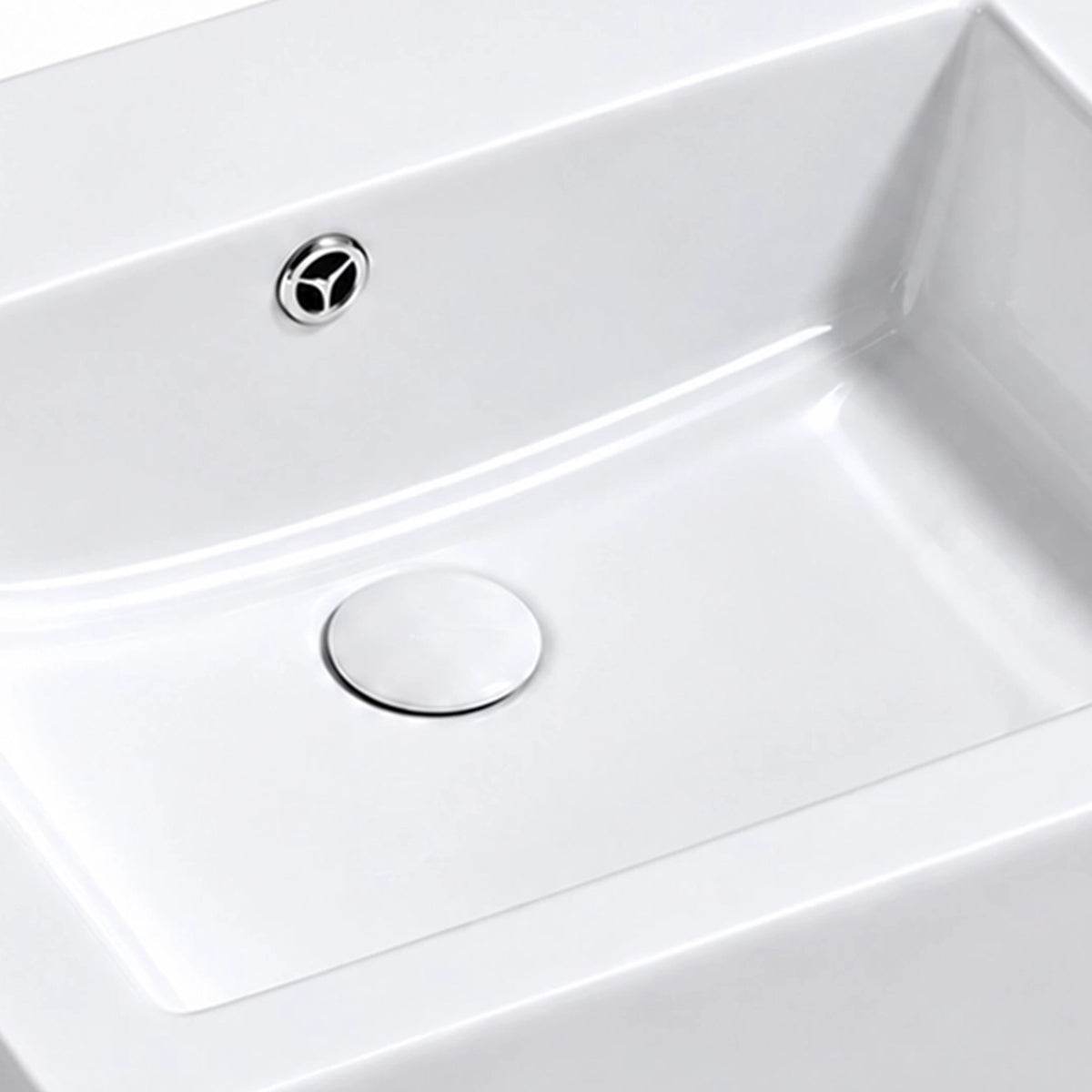 Close-up of the white rectangular ceramic semi-recessed bathroom sink showing the integrated overflow opening, smooth basin surface, and drain cover.