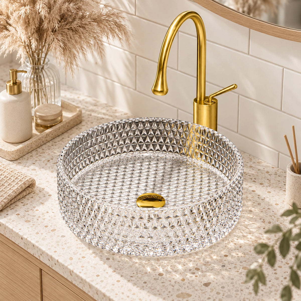 Round diamond-cut clear glass vessel sink paired with gold faucet on speckled countertop in warm modern bathroom setting