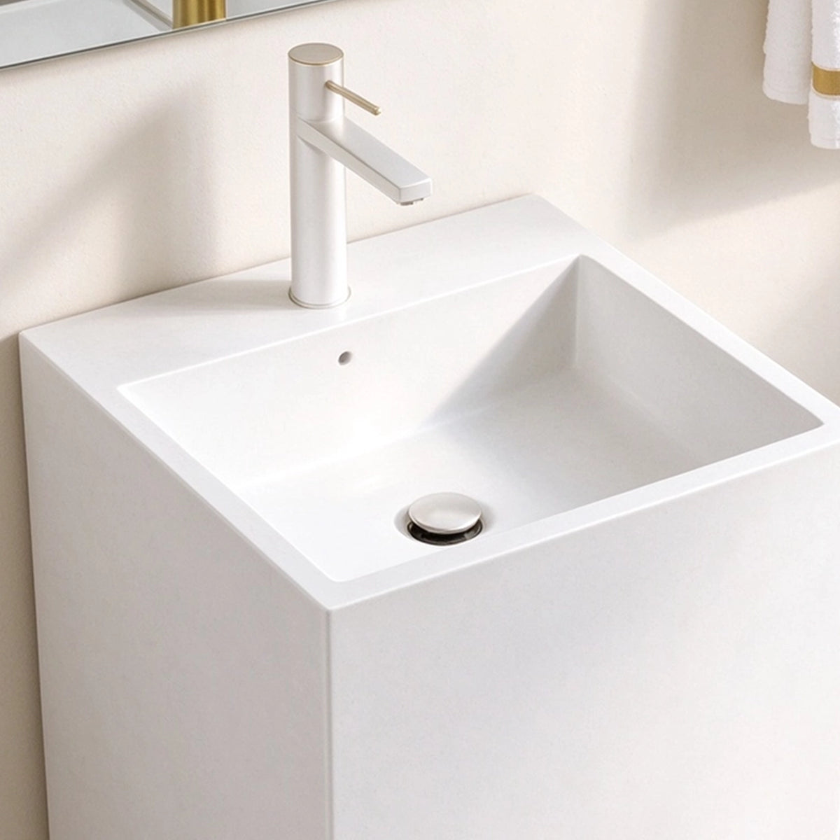 Close-up of the square basin, single faucet hole, and drain on a white freestanding bathroom sink