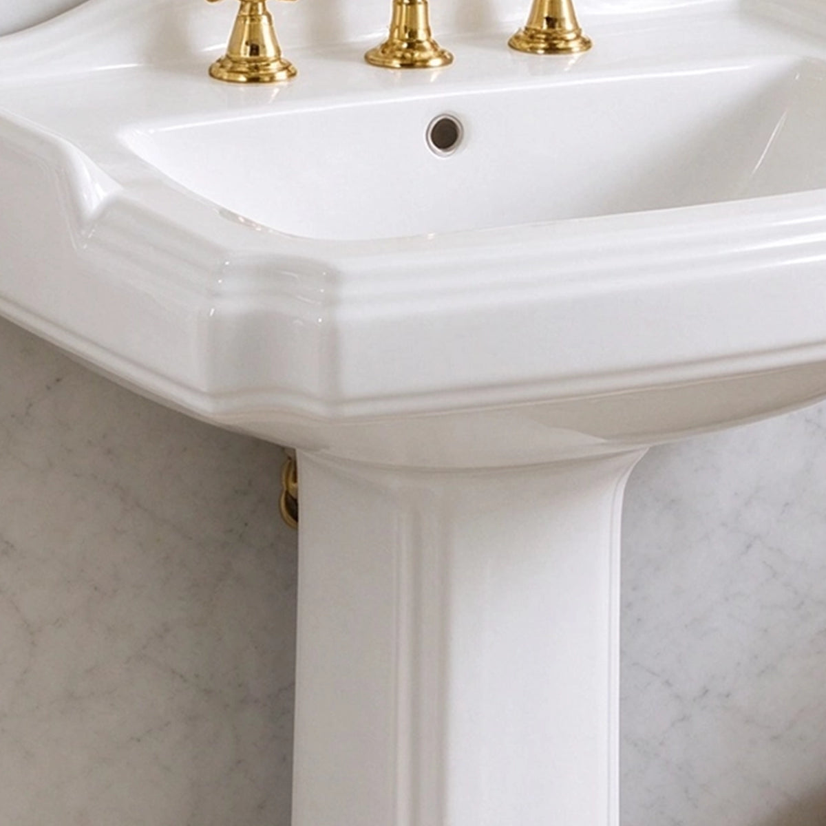 White ceramic pedestal sink detail with overflow opening and sculpted basin edge
