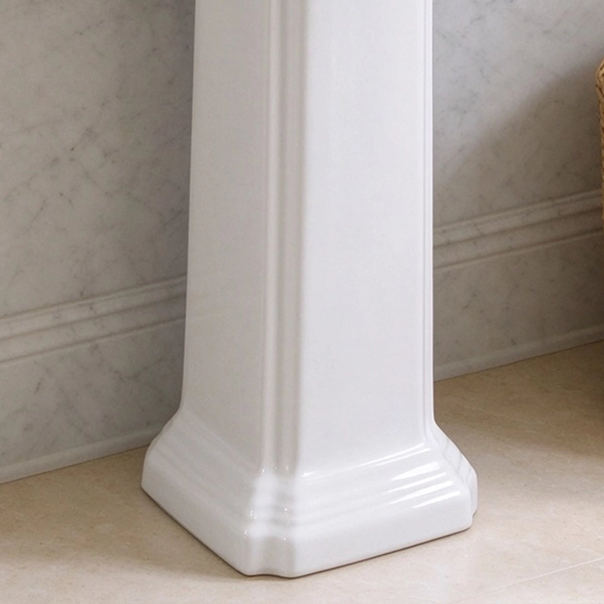 Close-up of the decorative ceramic pedestal base on a white bathroom sink
