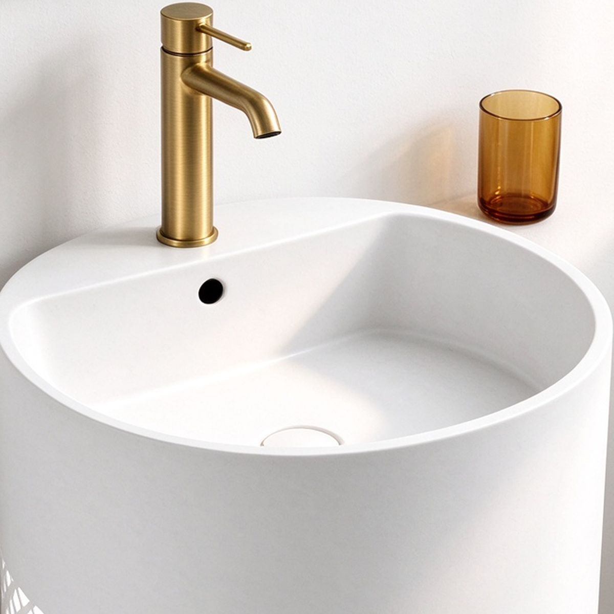 Close-up of white stainless steel pedestal bathroom sink basin with gold faucet and overflow