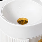 White round bathroom sink basin with gold-tone drain assembly and water droplets