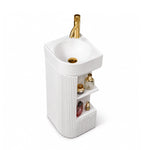 White freestanding bathroom sink with round basin, gold-tone faucet, and open storage shelves