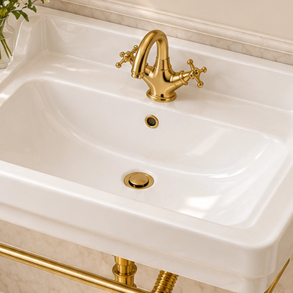 Close-up of a white rectangular console bathroom sink with a gold-tone faucet and integrated overflow opening