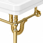 Close-up of the gold-tone console sink support frame and flexible drain hose beneath a white rectangular bathroom sink