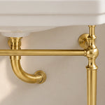 Close-up of the gold-tone support frame connection and drain pipe beneath the ceramic console sink