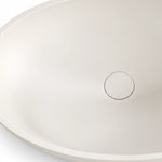 White engineered stone oval vessel bathroom sink with a close-up view of the drain opening