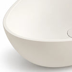 White engineered stone oval vessel bathroom sink with a close-up view of the smooth basin edge and drain opening
