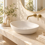 White oval vessel bathroom sink with wall-mounted faucet on a bathroom countertop