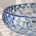 Blue glass round vessel bathroom sink with textured glass surface and blue-tinted rim
