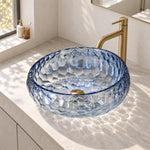 Blue glass round vessel bathroom sink with a textured surface and visible drain opening